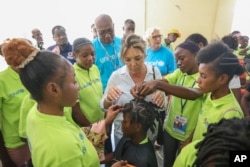 A high school student getting her hair done is approached by Yasmine Sherif, executive director of the U.N. global fund Education Cannot Wait, during her visit to the Jean Marie Vincent High School in Port-au-Prince, Haiti, July 25, 2024.