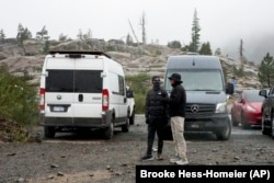 Snow falls on two motorists in Donner Summit, California, Aug. 24, 2024.