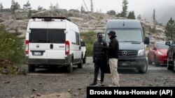 Snow comes down on two motorists, Aug. 24, 2024, in Donner Summit, Calif.