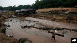 FILE - A resident carries wood to help dam up the Negro River near his houseboat, during a drought in Manaus, Amazonas state, Brazil, Oct. 16, 2023.