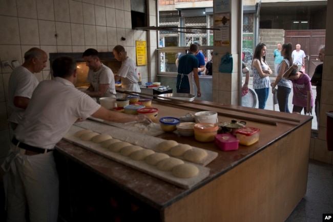 Para pembuat roti menyiapkan adonan dengan bahan-bahan yang dibawa oleh keluarga yang menunggu di luar, untuk menyiapkan dan memanggang pitalka di kota Prizren, Kosovo selatan, Jumat, 17 Juni 2016. (AP/Visar Kryeziu)