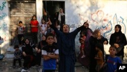 FILE - Palestinian women and children react following Israeli airstrikes targeting their neighborhood in Gaza City, Oct. 21, 2023.