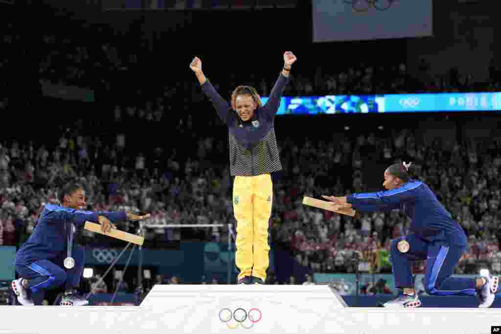 Silver medalist Simone Biles of the United States, left, and bronze medalist Jordan Chiles of the United States, right, bow to gold medalist Rebeca Andrade of Brazil during the medal ceremony for the women&#39;s artistic gymnastics individual floor finals at Bercy Arena at the 2024 Summer Olympics in Paris.