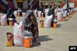 Perempuan Afghanistan duduk di sebelah bantuan makanan yang disalurkan oleh yayasan amal selama bulan suci Ramadan di Kandahar, 28 Maret 2023. (Sanaullah SEIAM / AFP)