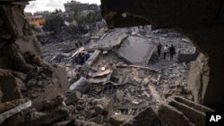 Palestinians inspect the rubble at the site of an airstrike that the Israeli military said targeted the house of an Islamic Jihad member, in Deir al-Balah, central Gaza Strip, May 13, 2023. 