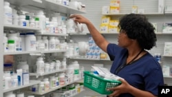 Lachandretta 'LaLa' Williams reaches for a pill bottle at MAC Pharmacy, May 29, 2024, in Cleveland.