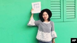 FILE - In this photo released by #FreeXueBing, Chinese journalist Huang Xueqin holds up a #METOO sign for a photo in Singapore in September 2017.