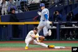 Los Angeles Dodgers designated hitter Shohei Ohtani (top) is hit first by San Diego Padres first baseman Jack Cronenworth during the seventh inning of baseball's season opener at the Gocheok Skydome in Seoul, South Korea, March 20, 2024. Forced out.