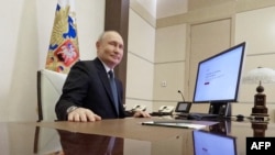 In this pool photograph distributed by Russia's state agency Sputnik, Russian President Vladimir Putin votes online in the presidential election at the Novo-Ogaryovo state residence, outside Moscow, on March 15, 2024.