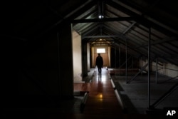 A man walks around one of the halls used as a detention and torture center, in the Argentine Navy School of Mechanics, ESMA, Museum and Site of Memory in Buenos Aires, Argentina, Tuesday, Sept. 19, 2023. (AP Photo/Rodrigo Abd)