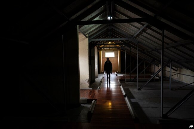 A man walks around one of the halls used as a detention and torture center, in the Argentine Navy School of Mechanics, ESMA, Museum and Site of Memory in Buenos Aires, Argentina, Tuesday, Sept. 19, 2023. (AP Photo/Rodrigo Abd)