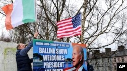 Ray Clarke, left, and Eddie Ruane put up flags in Ballina, Ireland, April, 4, 2023. Biden is scheduled to visit the town next week, part of a trip to Ireland and Northern Ireland.