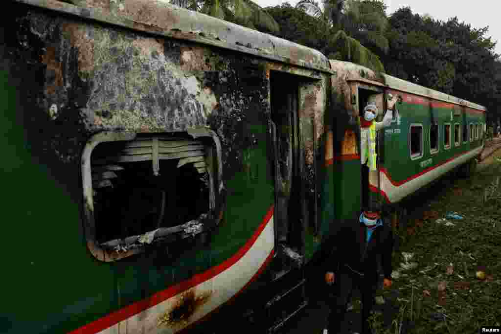 Crime Scene Unit members inspect the passenger train that was set on fire during a countrywide strike called by the Bangladesh Nationalist Party, ahead of the general election, in Dhaka.