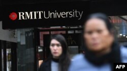 Warga berjalan melewati papan nama universitas Australia di pusat bisnis Melbourne pada 10 Juni 2020. (Foto: AFP)