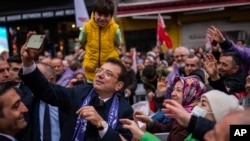 FILE - Istanbul Mayor and Republican People's Party, or CHP, candidate Ekrem Imamoglu takes photographs with supporters during a campaign rally in Istanbul, Turkey, March 21, 2024.