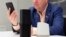 FILE - A man holds an iPhone next to an Amazon Echo, center, and a Google Home, right, in New York, June 14, 2018.  
