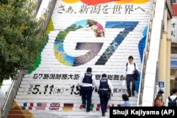 Sejumlah polisi menaiki anak tangga stasiun yang menampilkan logo Pertemuan Menteri Keuangan dan Gubernur Bank Sentral G7 di Niigata, Jepang, 10 Mei 2023. (Foto: Shuji Kajiyama/AP Photo)
