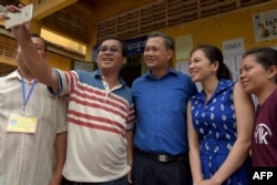FILE - Hun Manet (C), son of Cambodian Prime Minister Hun Sen and leader of the Cambodian People's Party (CPP), and his wife Pich Chanmoy (2nd R) poses for pictures with people after casting their ballots during the country's sixth general election in Phnom Penh on July 29, 2018.