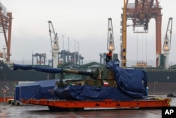 FILE - Seorang pekerja membuka penutup peralatan militer produksi korea Selatan, howitzer Thunder K9 di pelabuhan Angkatan Laut Polandia di Gdynia, 6 Desember 2022. (AP/Michal Dyjuk)