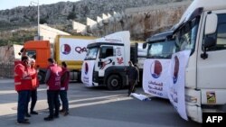 Men stand next to trucks, part of a convoy carrying earthquake aid provided by Qatar, at Syria's Bab al-Hawa border crossing with Turkey in the rebel-held northwestern province of Idlib, on Feb. 13, 2023.