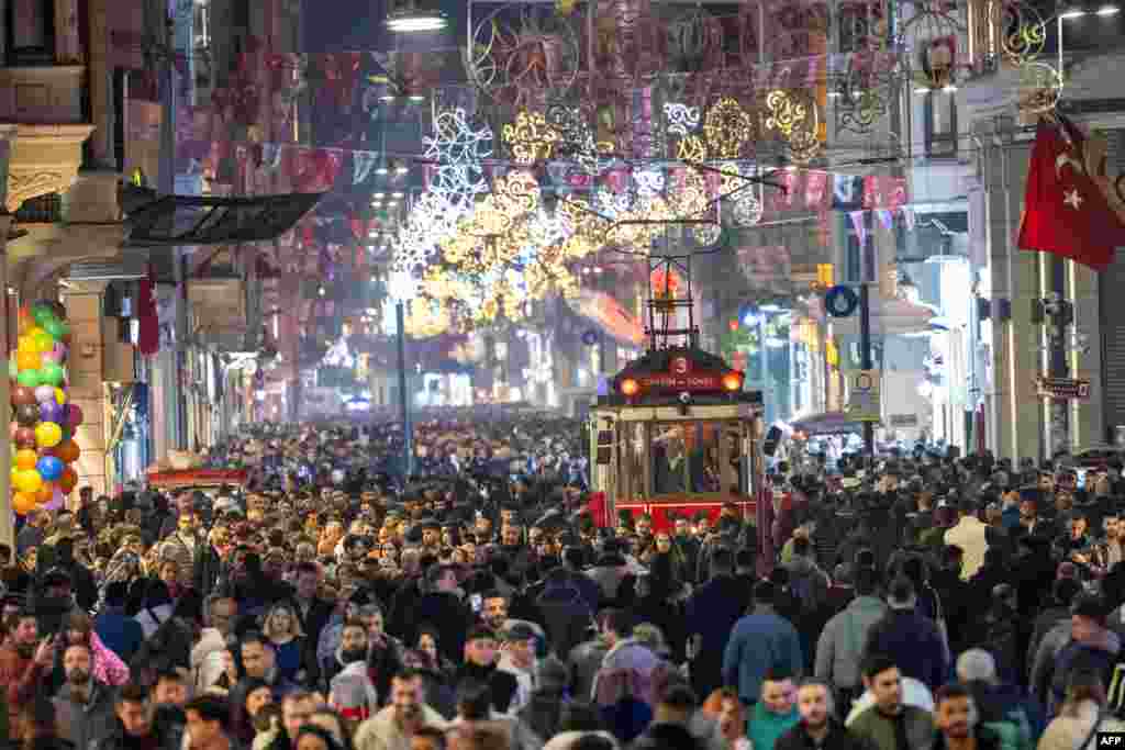 People walk past a historical tramway under Christmas light decorations on Istiklal street during preparations to celebrate the New Year 2024 in Istanbul, Turkey, Dec. 31, 2023. 