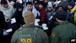 资料照片：在加利福尼亚州哈昆巴温泉镇附近的一处临时山地营地内，美国边境巡逻人员要求越过美国-墨西哥边界寻求庇护的人排队。(2024年2月2日)