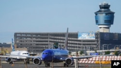 FILE - LaGuardia Airport's air traffic control tower, right, is shown as planes line up for take-off, May 25, 2023, in New York.