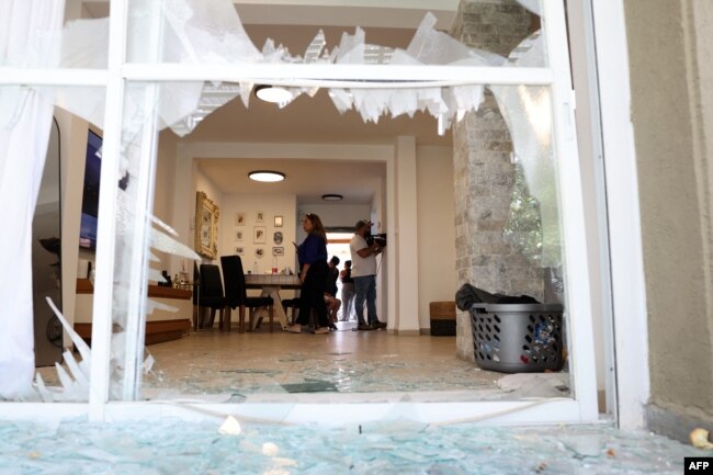 Residents check the damage caused by a rocket fired from Lebanon in the Israeli coastal town of Acre, Aug. 25, 2024.
