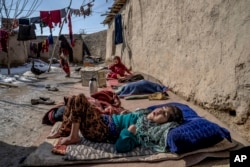 A sick and disabled girl lies in the open air in the yard, in a camp for internally displaced families on the outskirts of Kabul, Afghanistan, Monday, Feb 6, 2023. Her mother has no money to treat her sick child. (AP Photo/Ebrahim Noroozi)