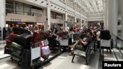 People sit near their luggage at the Beirut–Rafic Hariri International Airport, in Beirut, Lebanon, July 29, 2024.