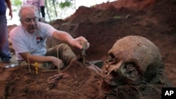 FILE - Rogelio Goiburú, a member of the Paraguayan Truth and Justice Commission, examines skeletal remains found at the headquarters of the National Police Special Forces in Asunción, Paraguay, March 19, 2013.