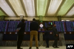 FILE - Brokers monitor an index board showing the latest share prices at the Pakistan Stock Exchange in Karachi, Jan. 26, 2023.