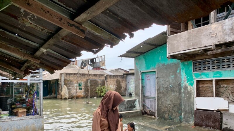 Seorang pelajar sedang melintasi kawasan banjir rob di Kecamatan Medan Belawan, Kota Medan, Sumatra Utara, Jumat 19 Mei 2023. (VOA/Anugrah Andriansyah)