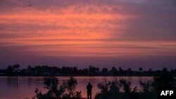 A man stands on the banks of the Shatt al-Arab waterway at sunset in the southern Iraqi city of Basra, on June 6, 2023.