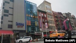 ARCHIVO – Se cree que un edificio de seis pisos con fachada de vidrio, en la foto, segundo desde la izquierda, en el barrio chino de Nueva York, opera un puesto de avanzada de la policía extranjera para China.