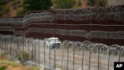 FILE - A vehicle drives along the US side of the US-Mexico border wall in Nogales, Ariz., June 25, 2024.