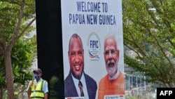 A security worker stands next to a banner featuring Papua New Guinea's Prime Minister (L) and India's Prime Minister Narendra Modi in Port Moresby, May 18, 2023. 