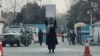 Seorang mahasiswi melakukan aksi protes seorang diri, menentang larangan pendidikan tinggi bagi perempuan, di hadapan para anggota Taliban yang berjaga di luar Universitas Kabul, 25 Desember 2022. (AFP)