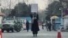FILE - A young woman protests alone against a Taliban ban on women's higher education, outside Kabul University, as Taliban guards stand by, in Kabul, Afghanistan, Dec. 25, 2022. 