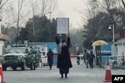 Marwa staged a solo protest outside Kabul University, against the ban on studying for women, in front of members of the Taliban standing guard in Kabul, December 25, 2022 (AFP)