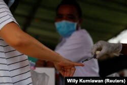 Petugas membubuhi tinta biru pada jari usai mencoblos saat Pilkada di Tangerang, 9 Desember 2020. (Foto: REUTERS/Willy Kurniawan)