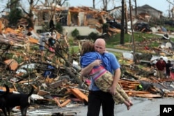 A man carries a young girl who was rescued after being trapped with her mother in their home after a tornado hit Joplin, Mo., May 22, 2011. (AP Photo/Mike Gullett)