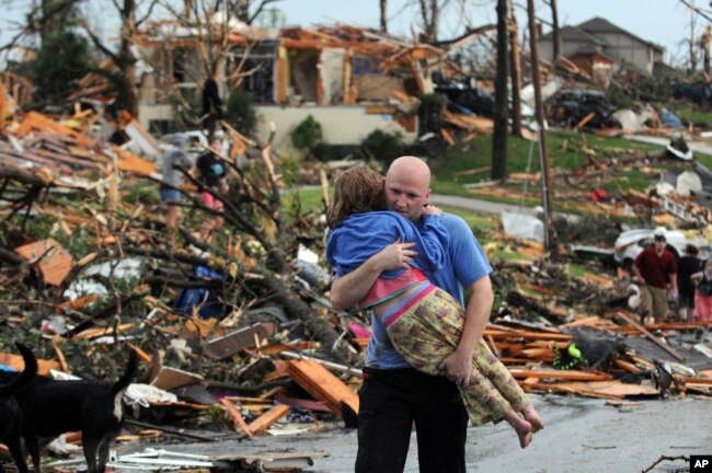 A man carries a young girl who was rescued after being trapped with her mother in their home after a tornado hit Joplin, Mo., May 22, 2011. (AP Photo/Mike Gullett)