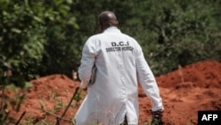 FILE - An officer with the Kenyan Directorate of Criminal Investigations (DCI) walks next to dug up ground at the mass-grave site in Shakahola, outside the coastal town of Malindi, on April 25, 2023. 