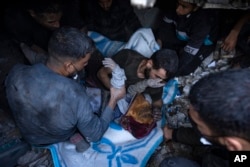 Palestinians pull a body out of the rubble of a residential building destroyed in an Israeli airstrike, in Rafah, southern Gaza Strip, Dec. 15, 2023.