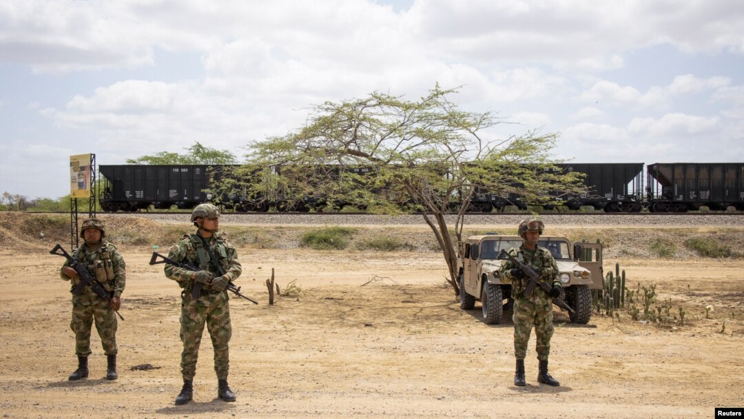 ARCHIVO - Soldados montan guardia cerca de los vagones de tren cargados de carbón, antes de que los indígenas wayuu de las comunidades cercanas levantaran un bloqueo de una línea férrea en Puerto Bolívar, Colombia, el 7 de abril de 2023.