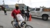 A man cycles past police officers on patrol near the airport, in Port-au-Prince, Haiti, June 1, 2024. 