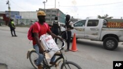 A man cycles past police officers on patrol near the airport, in Port-au-Prince, Haiti, June 1, 2024. 