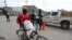 A man cycles past police officers on patrol near the airport, in Port-au-Prince, Haiti, June 1, 2024. 