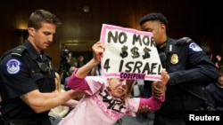 Seorang pengunjuk rasa anti-perang yang membawa tulisan "No More $$$ 4 Israel" (seruan untuk menghentikan bantuan AS untuk Israel) "diamankan" oleh polisi selama sidang Komisi Senat AS di Gedung Capitol, Washington, DC Selasa (31/10).